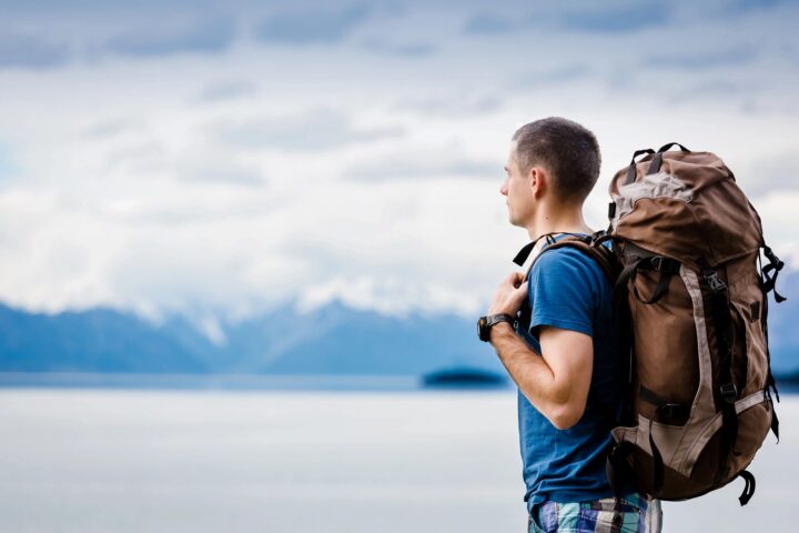 Hiker with backpack pausing to take in the view, the kind of long outdoor day where a Mizu M8 or V8 water bottle stays in hand. Stock photo courtesy of GoDaddy Stock Photos.